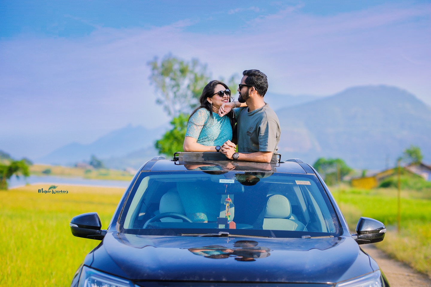 Pre wedding couple emerging from a luxury car sunroof in scenic mountain landscape
